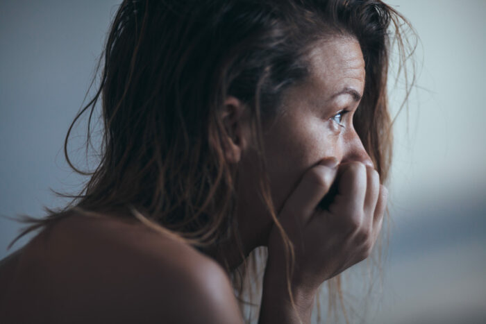 Woman sitting alone and depressed with face in hands