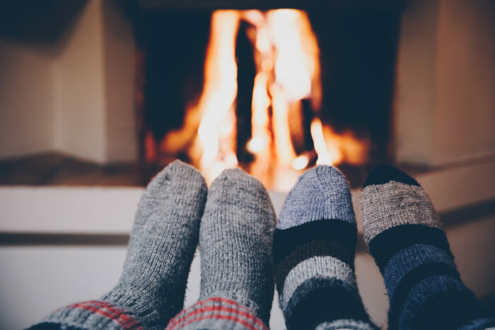 Feet in wool striped socks by the fireplace. Relaxing at Christmas fireplace on holiday evening.