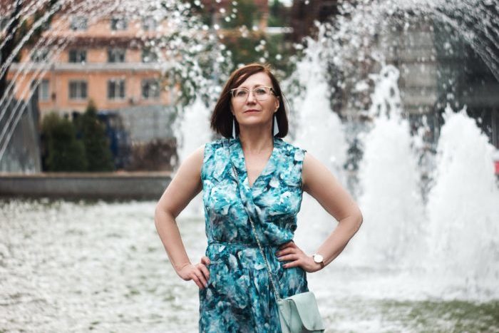 confident woman standing in front of fountain with hands on hips