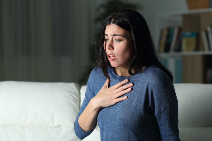 Woman suffering an anxiety attack alone in the night and has their hand on their chest