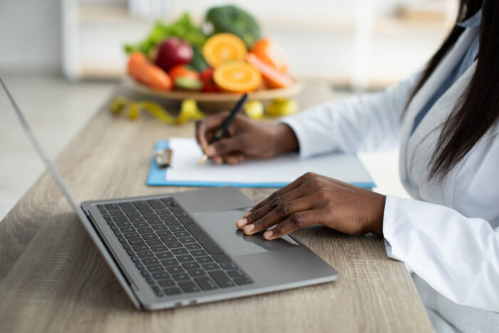 Working process. Dietitian creating diet plan for patient or counting calories, working on laptop