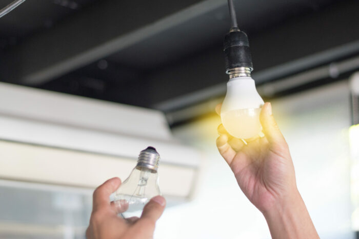 Power saving concept. Person changing compact-fluorescent (CFL) bulbs with new LED light bulb.