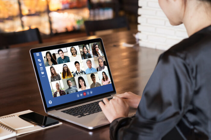 Back view of young asian business woman work remotely at home video conference remote call to corporate group. Meeting online,videocall, group discuss online concept with screen of teamwork on laptop.