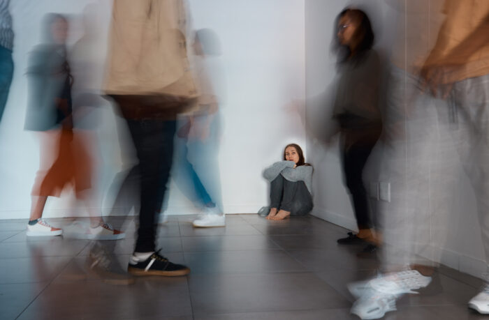 Shot of a young woman sitting on the floor with people around her