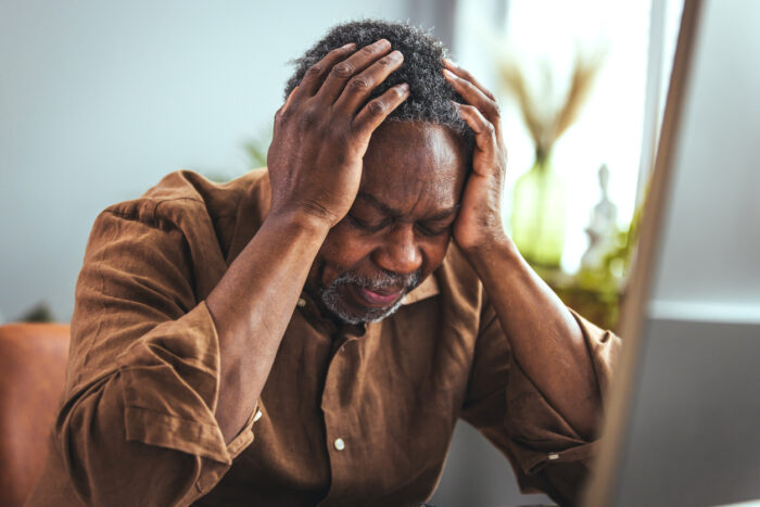 Senior man worried with head in their hands and looking down