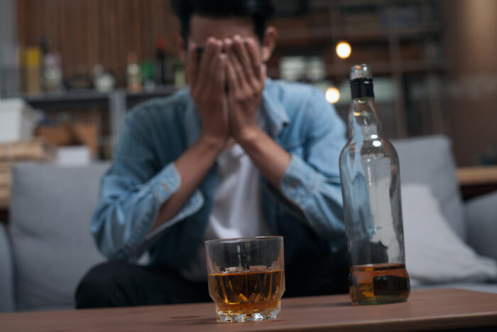 Alcoholism or Alcoholic concept : Close up young guy feeling depressed drinking alcohol alone in pub or bar because life problem or stress.