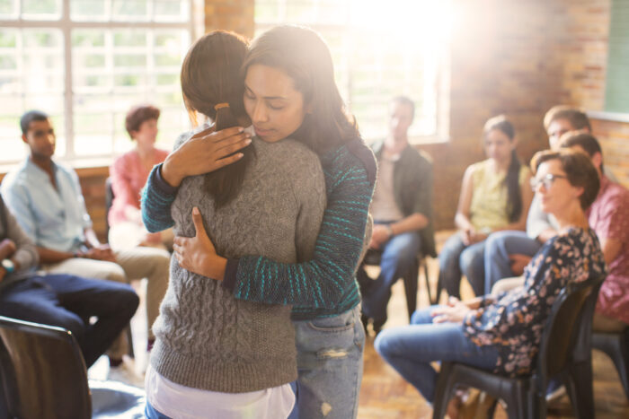 Women hugging in group therapy session