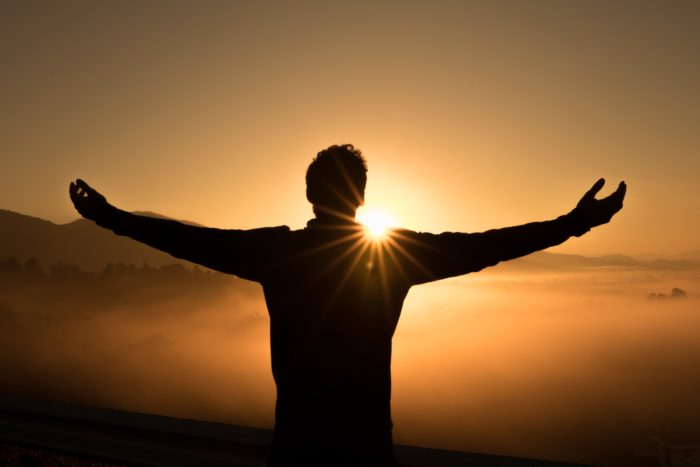 man standing with arms outstretched over vista