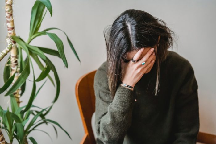 person stressed with their hand on their face while sitting in a chair