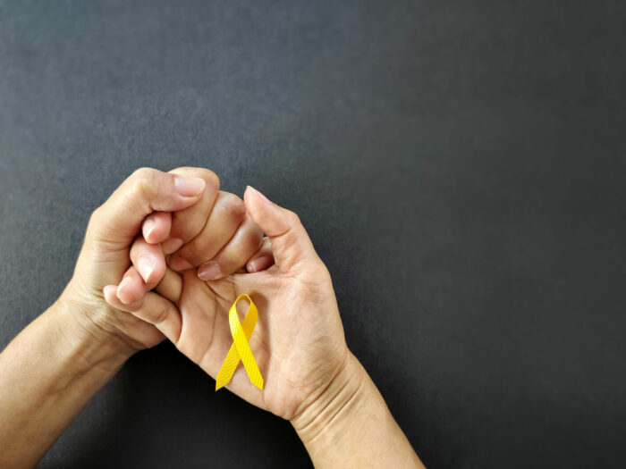 Hands holding a yellow ribbon, a yellow ribbon symbolize the world suicide prevention day