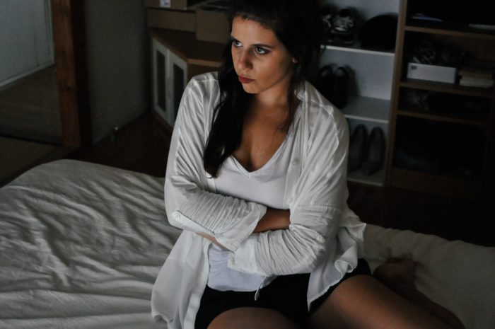 upset woman with arms crossed sitting on bed