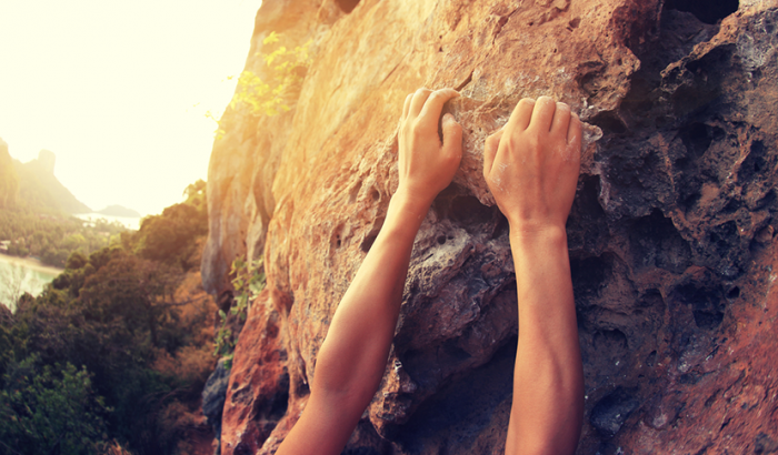 gritty person hanging onto rock